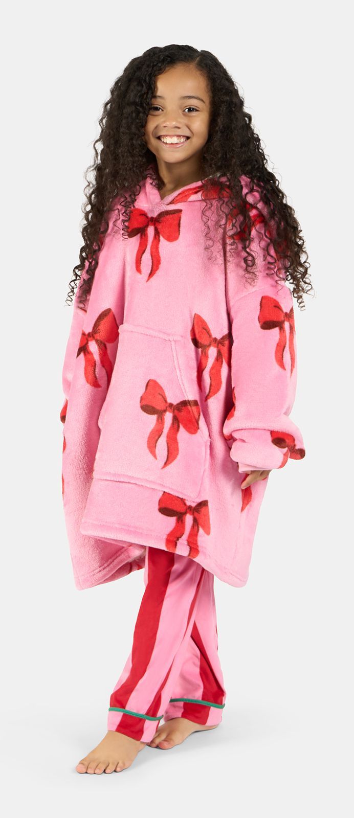 Young person smiles, wearing a pink bow-patterned oversized hoodie and pants.