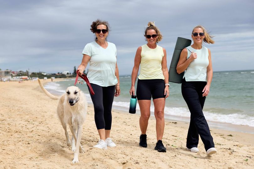 Three ladies - wearing Happy Healthy Fitness Activewear walking together along the beach in Melbourne.
