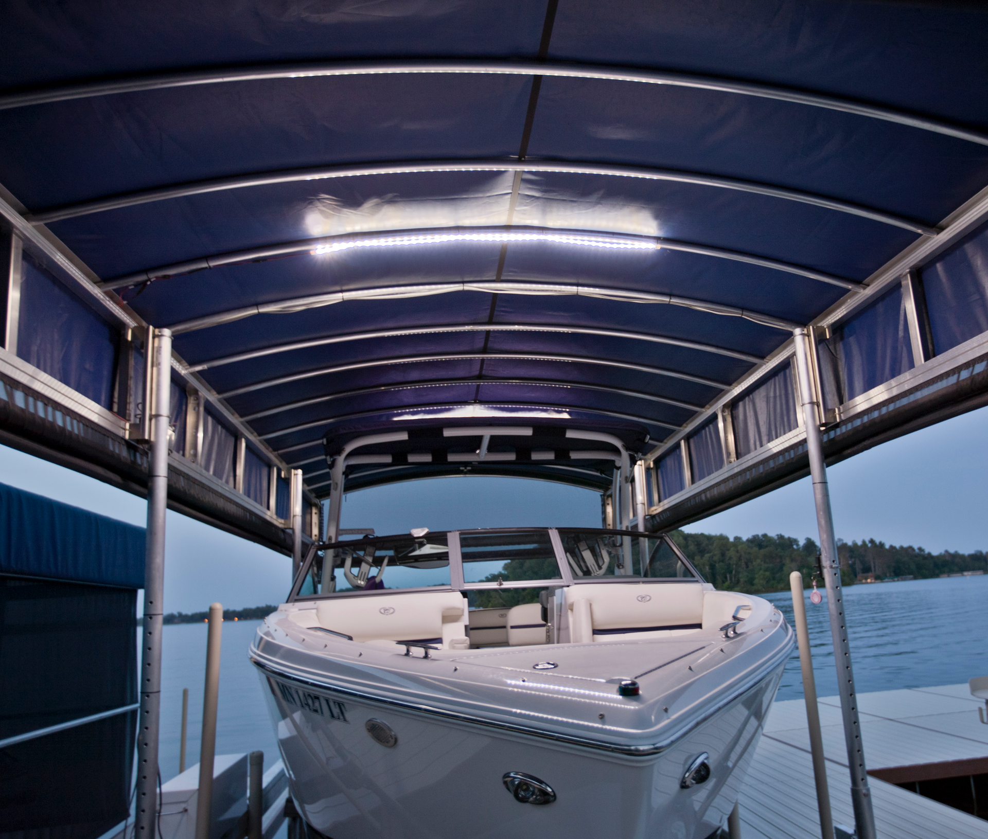 A boat is sitting under a canopy on a dock.