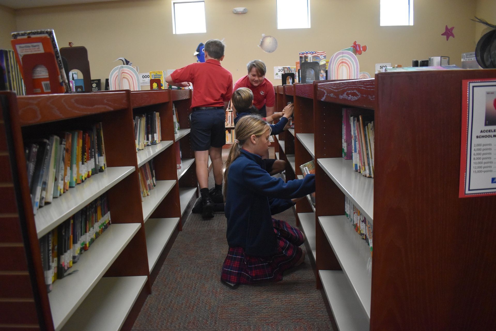 Children in a library looking at books on shelves