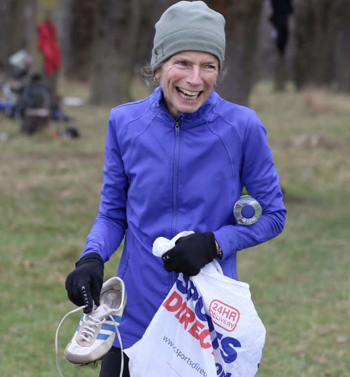 A woman in a purple jacket is holding a sports direct bag