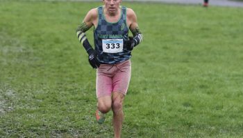 A man in pink shorts is running on a grassy field.