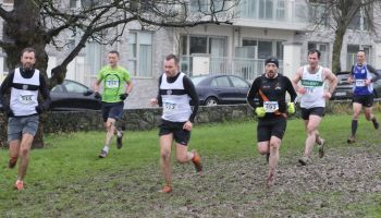 A group of men are running in a park.