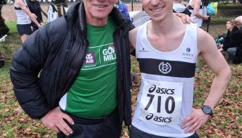 A man in a green shirt is standing next to a man in a white tank top with the number 710 on it.