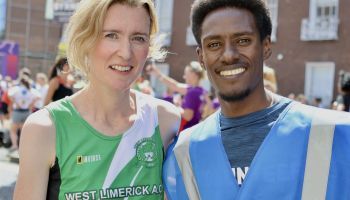 A man and a woman are posing for a picture together . the man is wearing a blue vest.