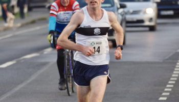 A man is running down a street with a number 14 on his shirt.