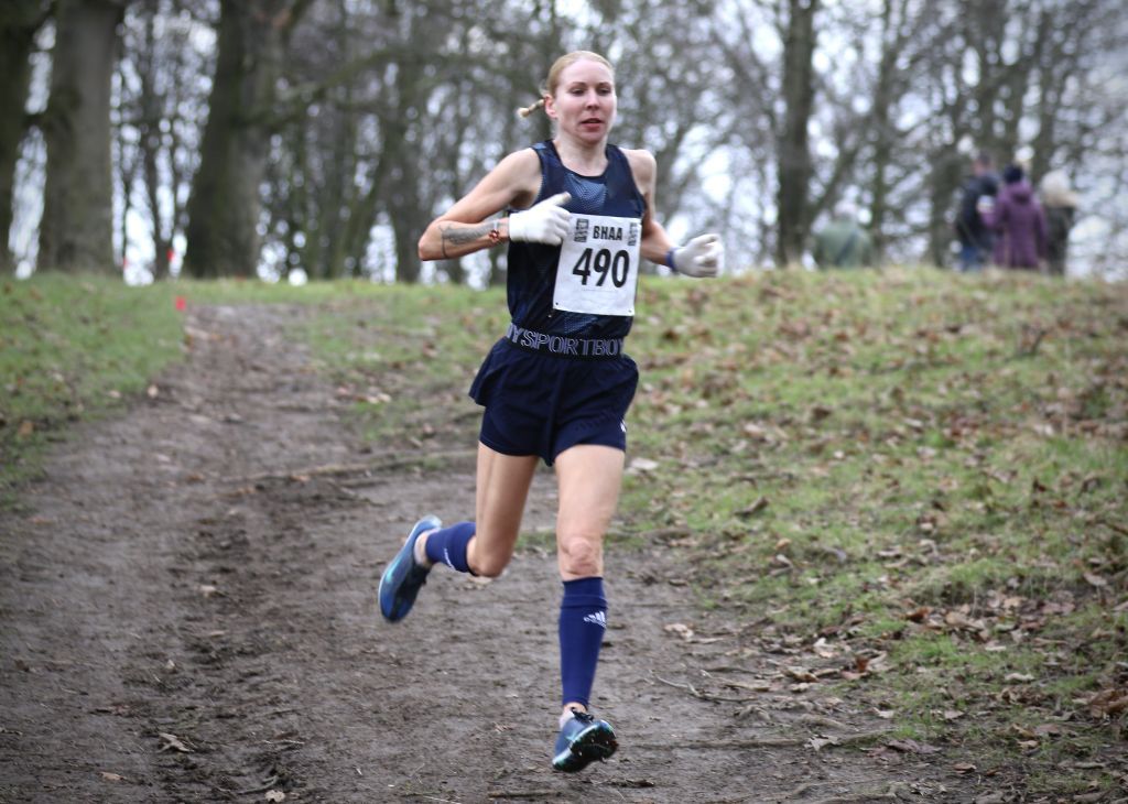 A woman is running a cross country race in a park.