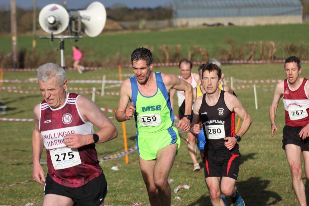 A group of men are running on a grassy field.