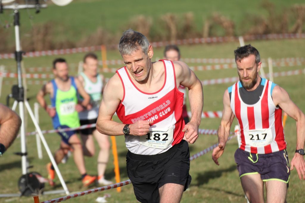 A group of men are running a race on a grassy field.