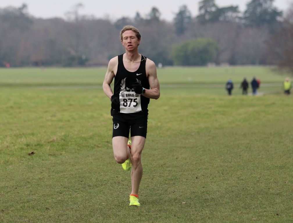 A man running in a field with the number 875 on his shirt