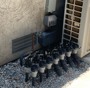 Black and white valves with gray caps, copper pipe and electrical components next to an outdoor air conditioning unit.