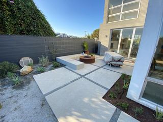 Modern outdoor patio with concrete pavers, fire pit, bench, and contemporary building.