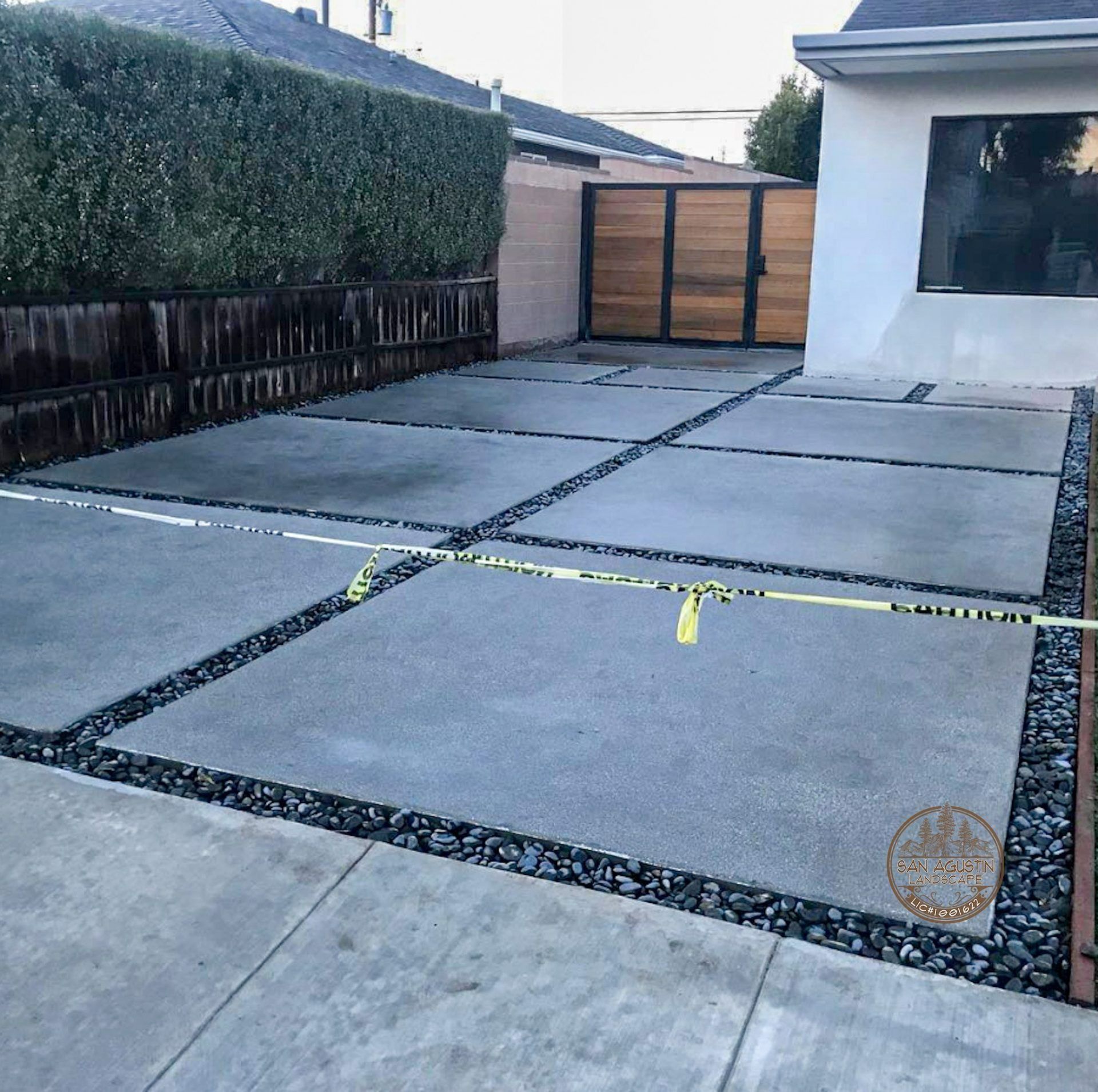 Concrete driveway with stone borders and wooden gate.