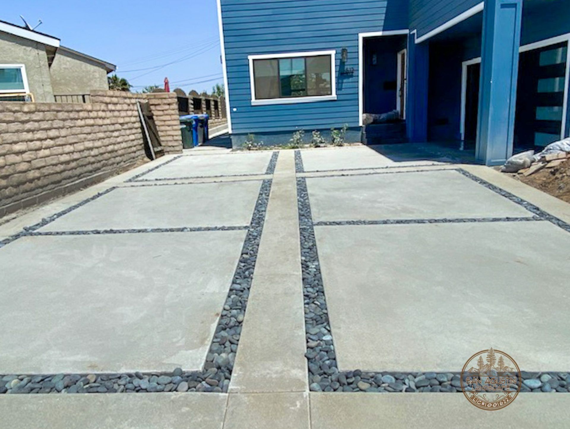Concrete driveway with dark gray rock accents in front of a blue house.