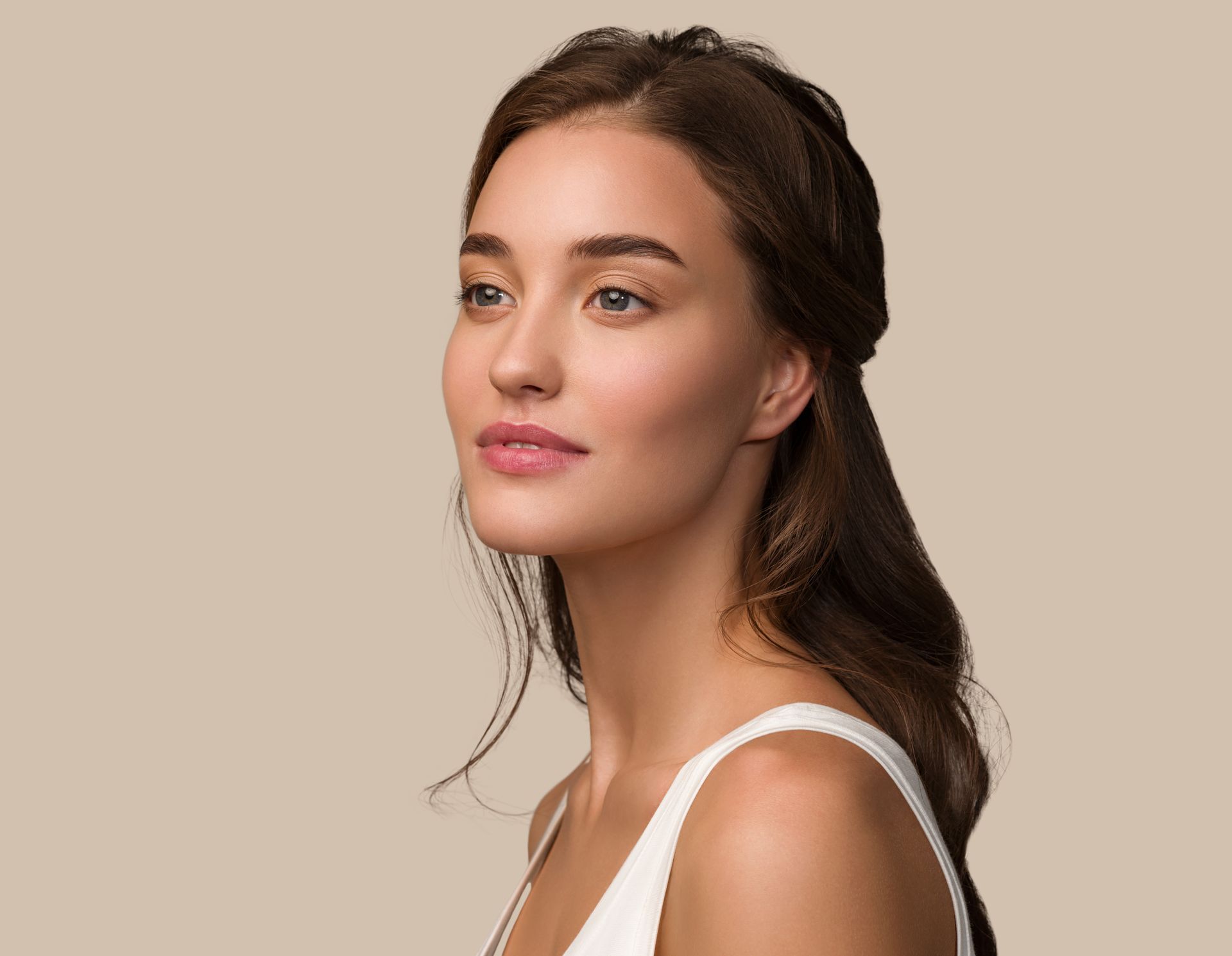 The woman is wearing a white tank top and looking to the side.