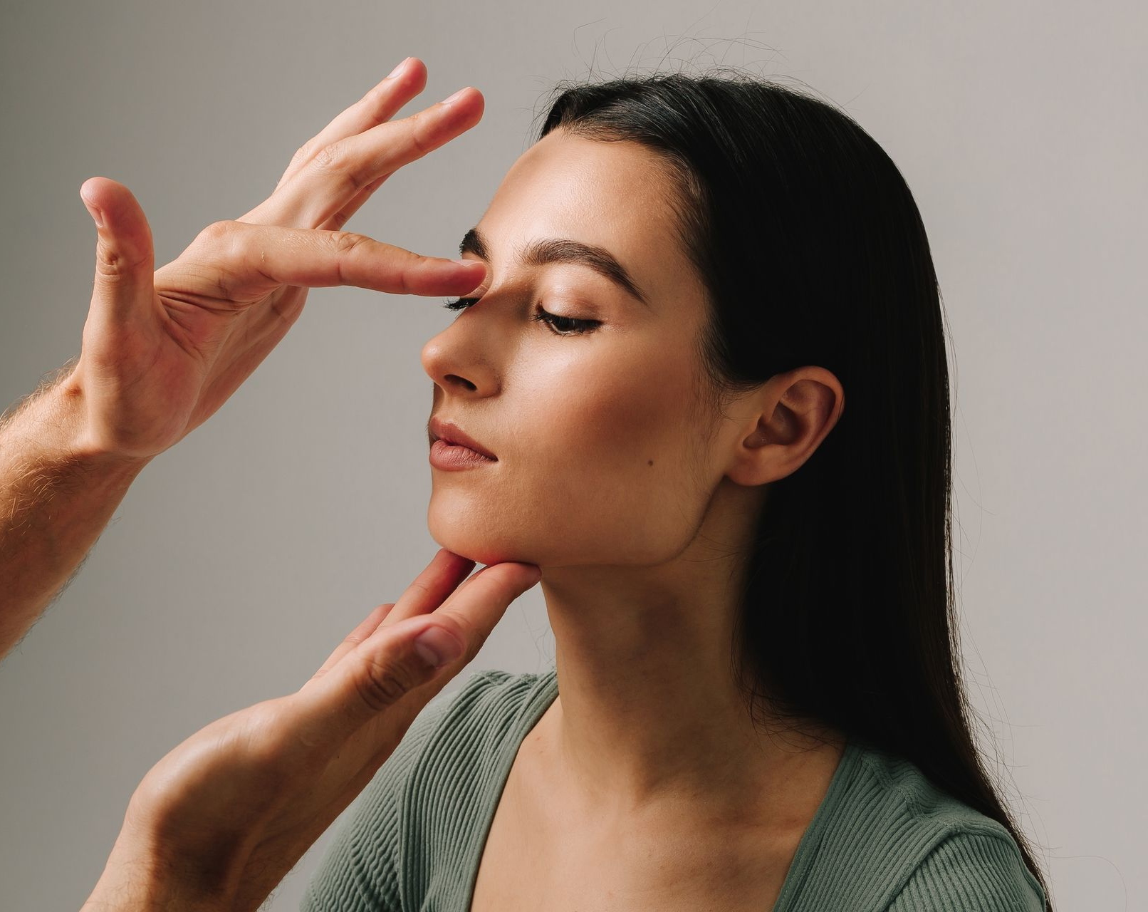 A woman is touching her face with her hand and looking at the camera.
