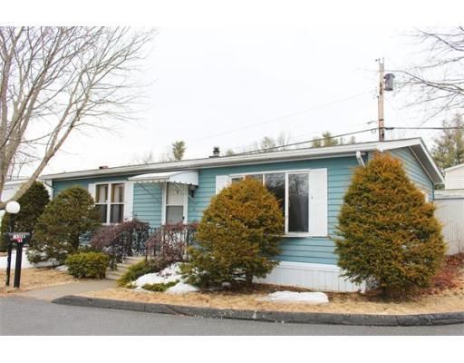 A blue mobile home with trees in front of it