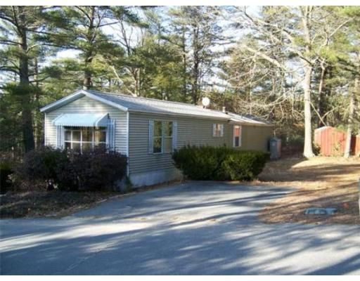 A small house is surrounded by trees and bushes
