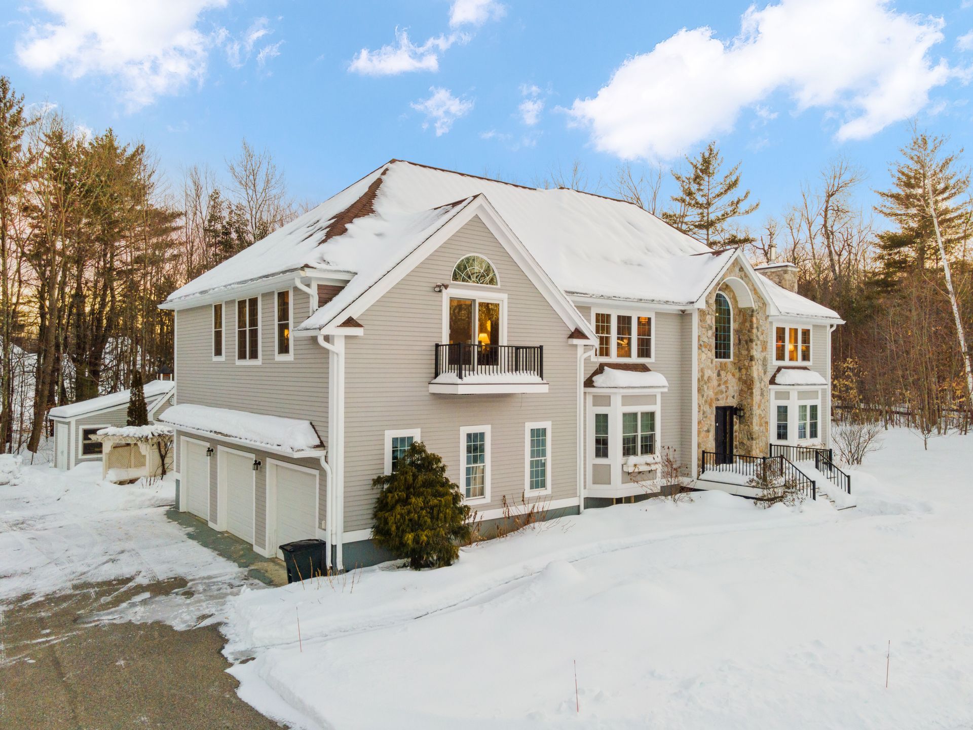 A large house is surrounded by snow and trees.