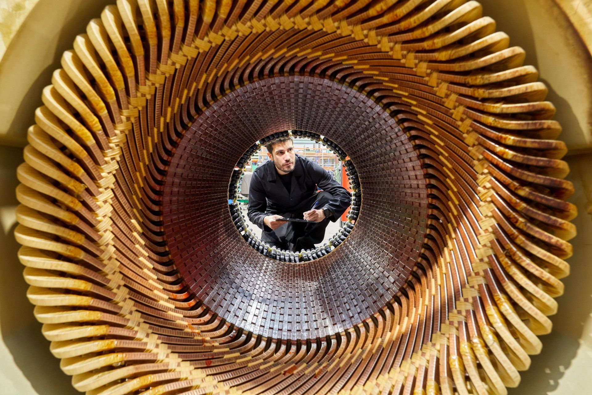 Un hombre en una estructura similar a un túnel, hecha de costillas doradas y curvas. Mira a la cámara.