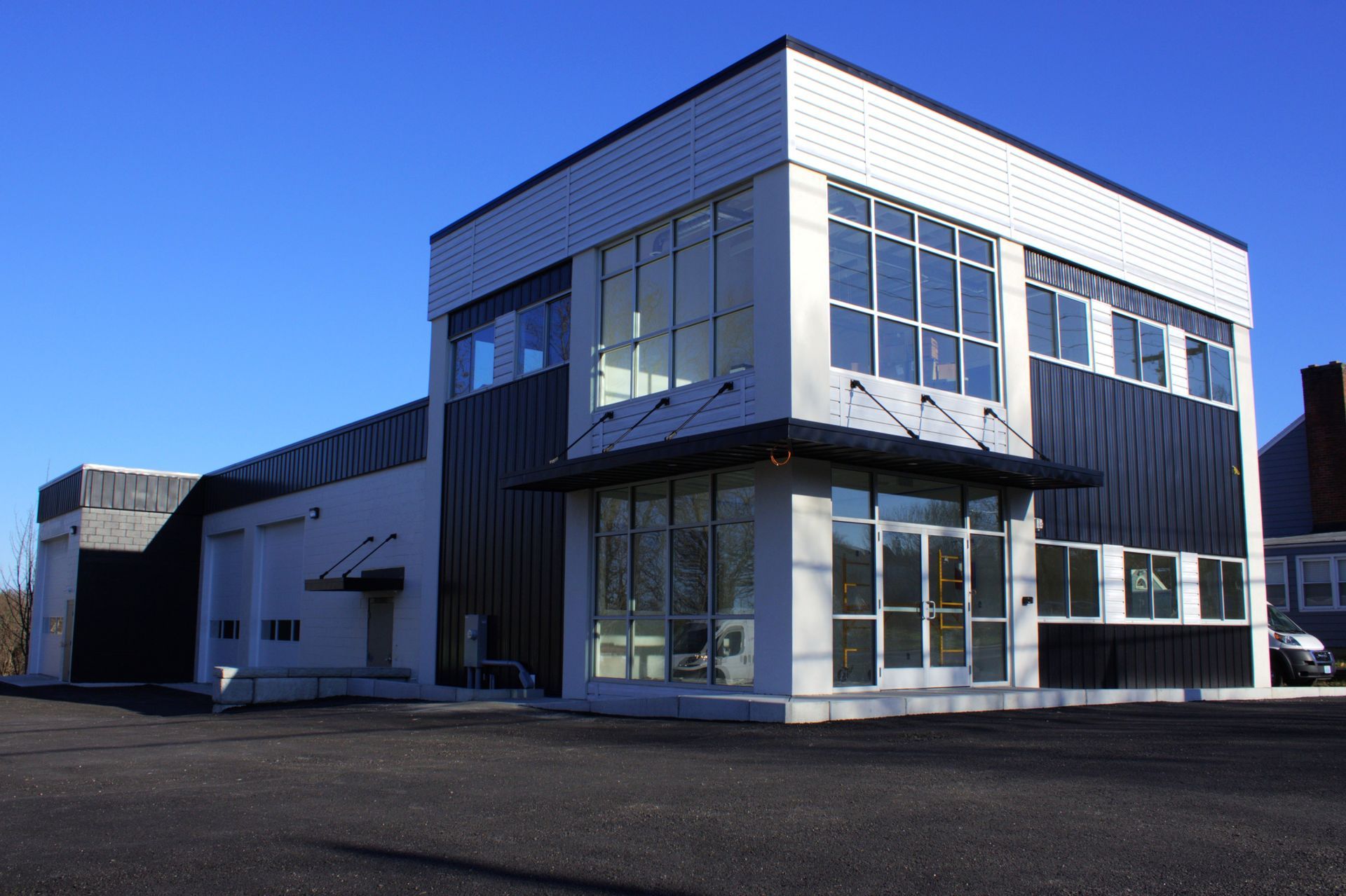 Modern commercial building with white and dark gray exterior under a clear blue sky