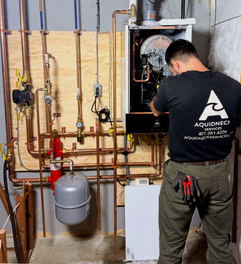 Gray and red boiler unit with pipes and gauges in a basement utility room