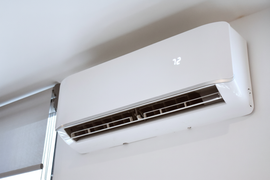 White wall-mounted air conditioner near the ceiling with vents open