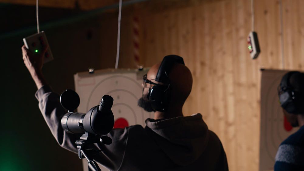Person aiming a handgun at an indoor shooting range with a target visible ahead