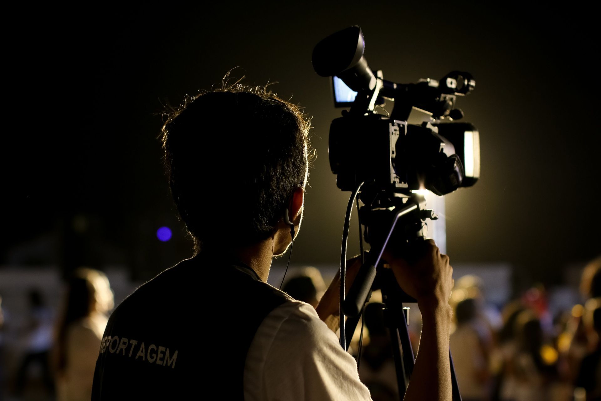 Person filming with a video camera at a nighttime outdoor event