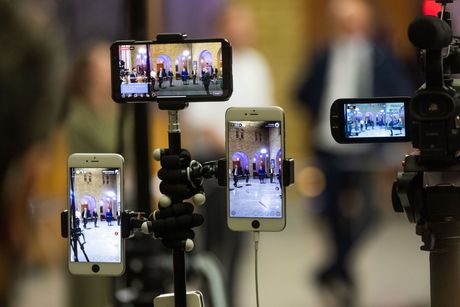 Multiple smartphones on tripods recording a stage performance in a dim indoor venue