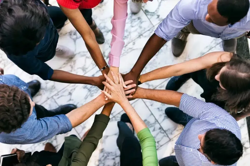 A group of people are putting their hands together in a circle.