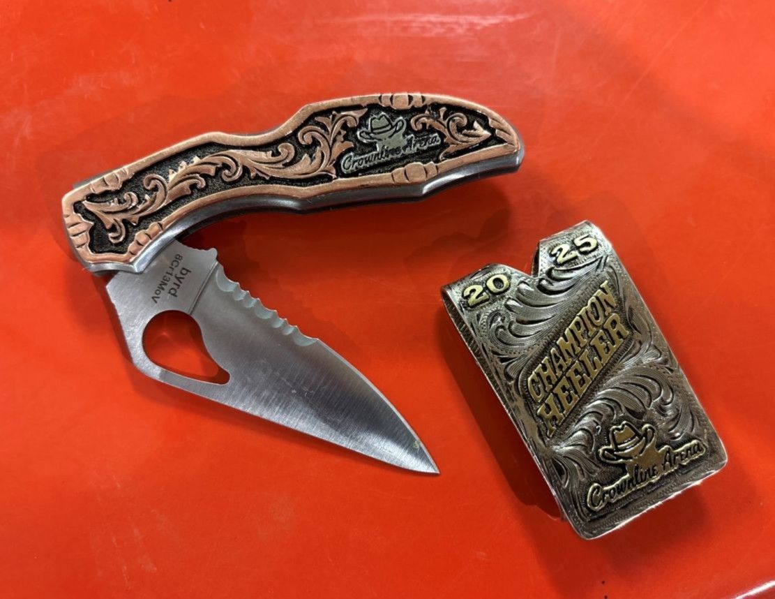 Pocket knife with engraved copper handle and a silver and gold engraved lighter resting on a red surface.