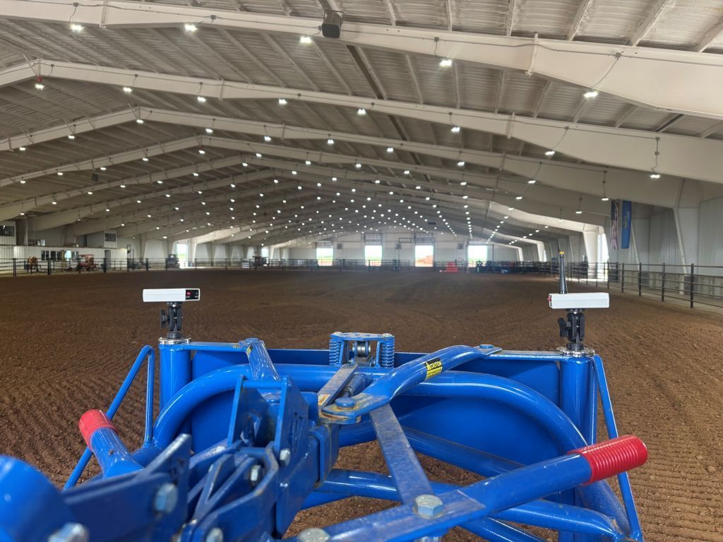 A blue tractor is parked inside of a large building.