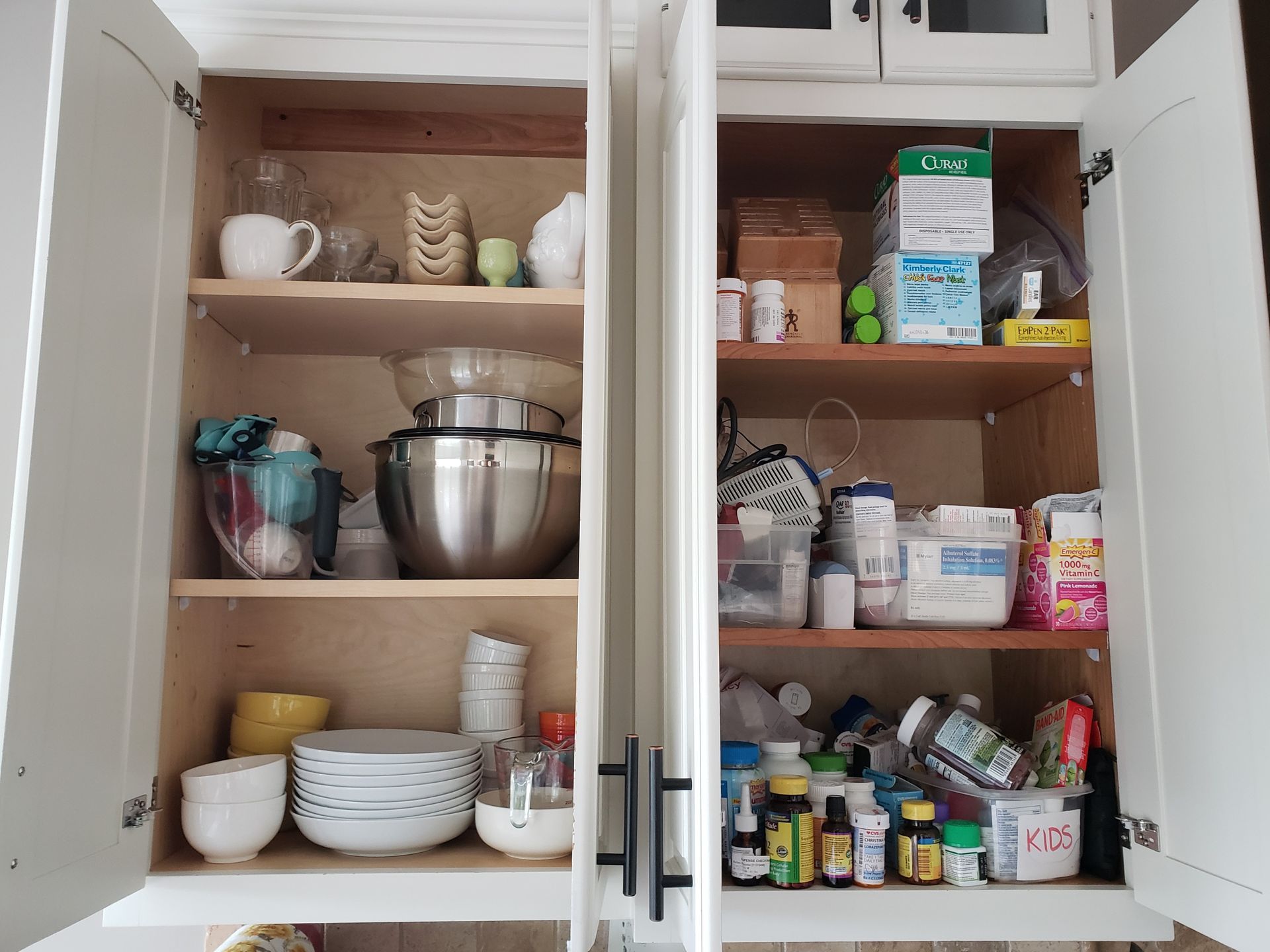 A kitchen cabinet filled with bowls plates and bottles