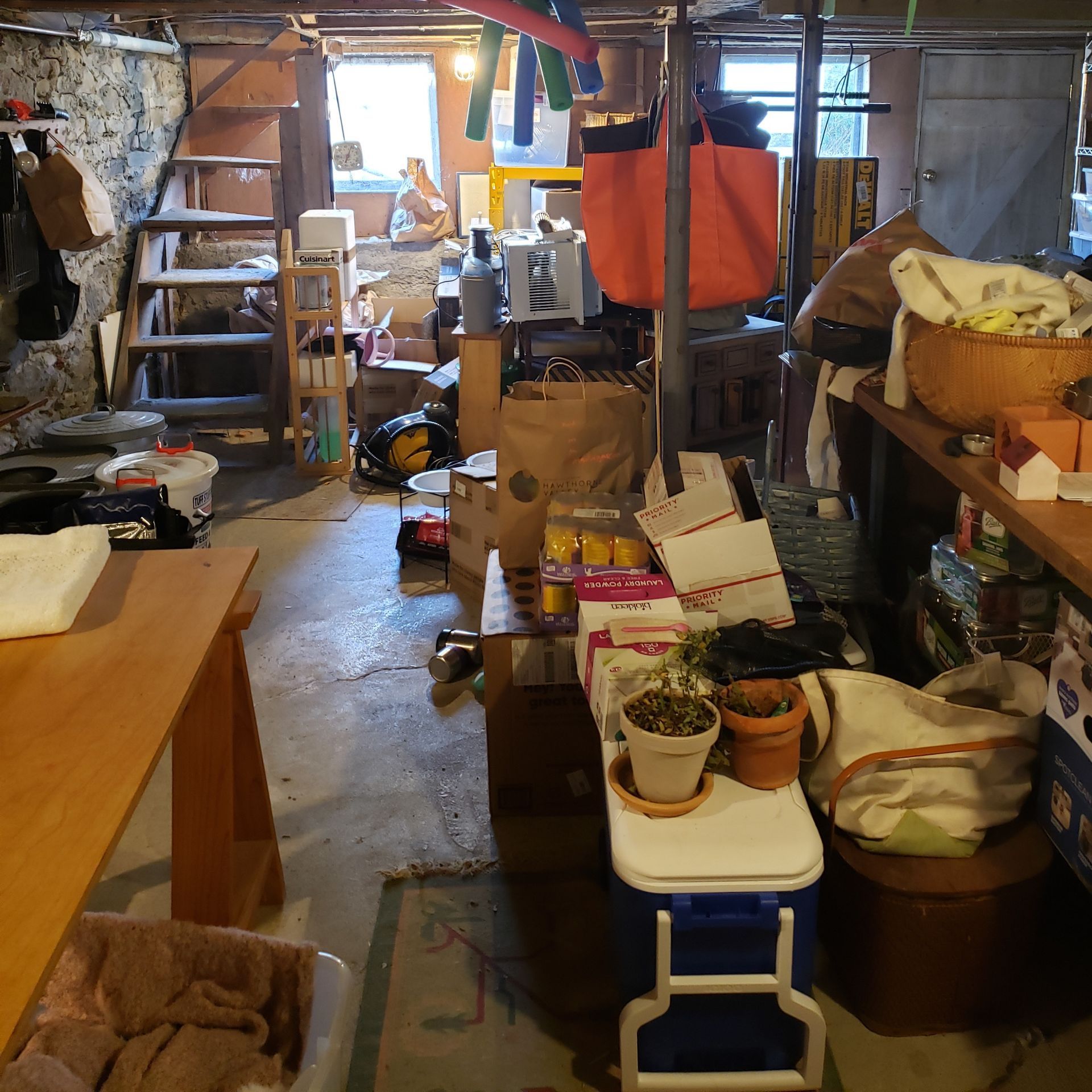 A cluttered room with a blue cooler on the floor