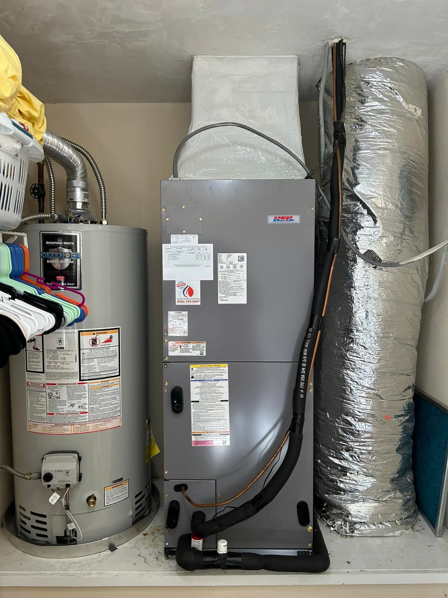 Three water heaters in a utility closet, with gray tankless unit centered and insulated ducts on the right.