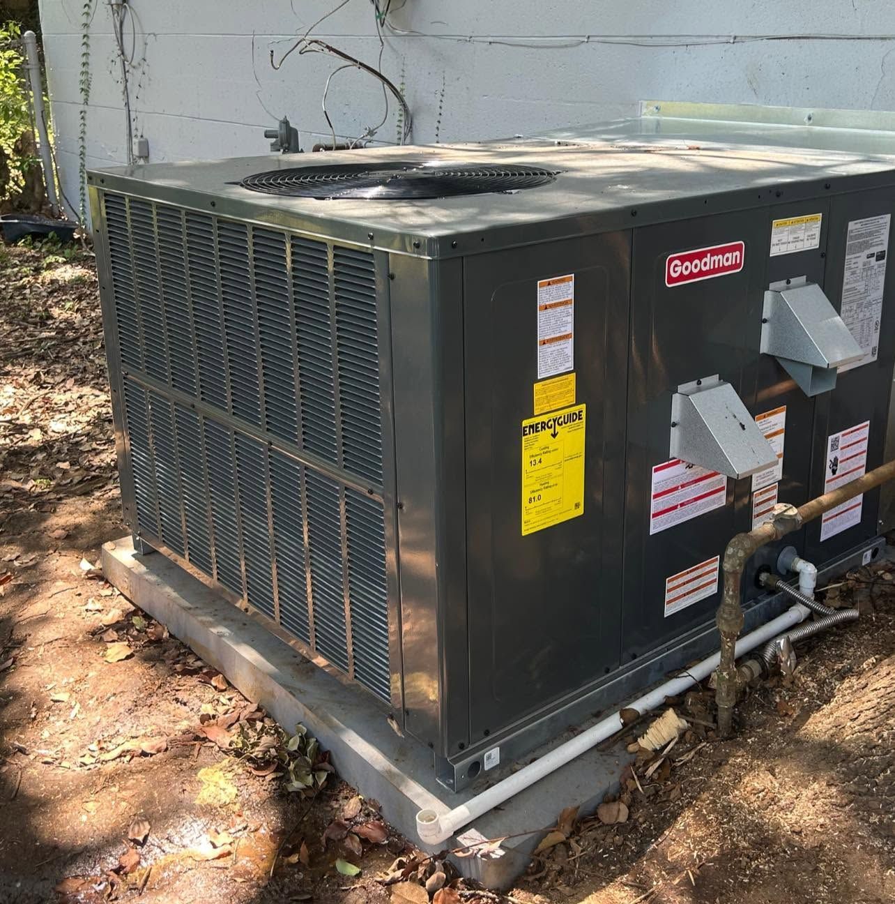 Outdoor rooftop HVAC unit with dark gray metal panels and visible warning labels.