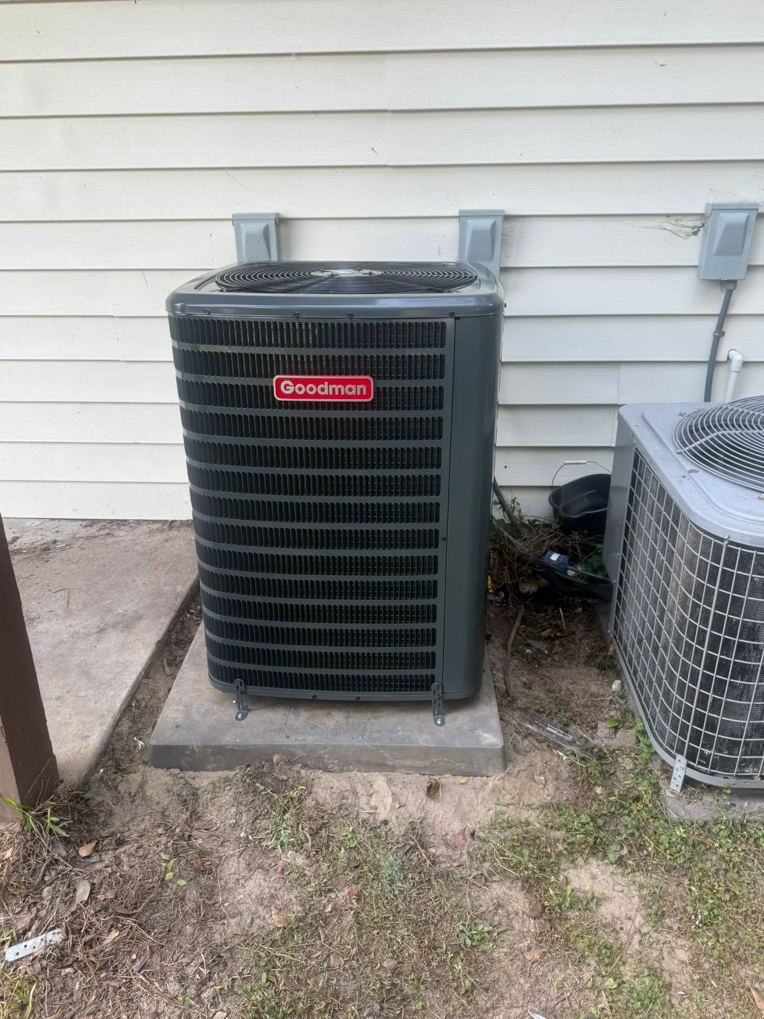 Outdoor HVAC condenser unit beside a house, with a second unit partially visible on the right.