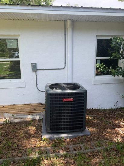 Outdoor air conditioning units lined up against a red brick wall in bright sunlight