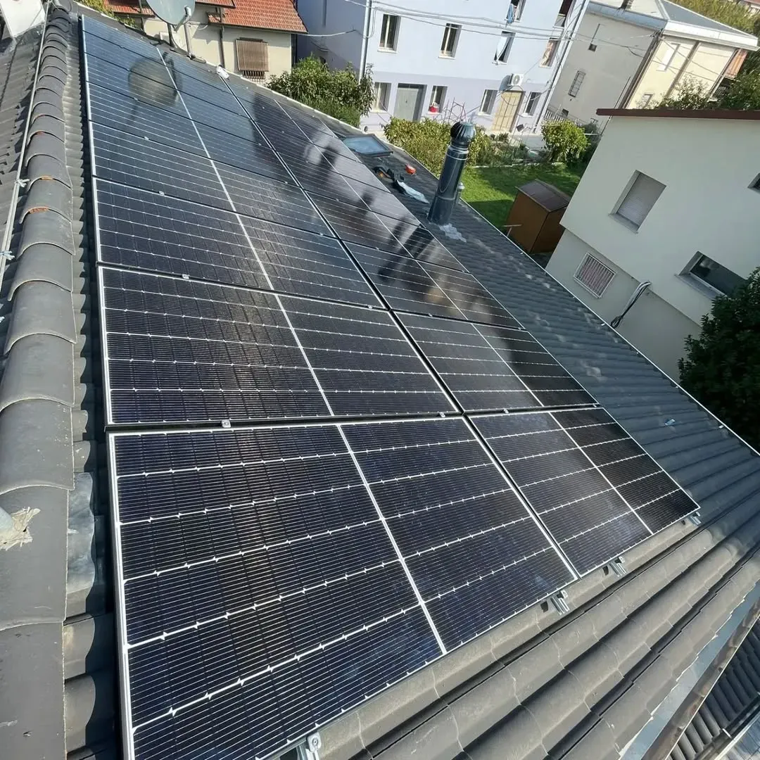 Pannelli solari installati su un tetto residenziale rivestito di tegole scure.