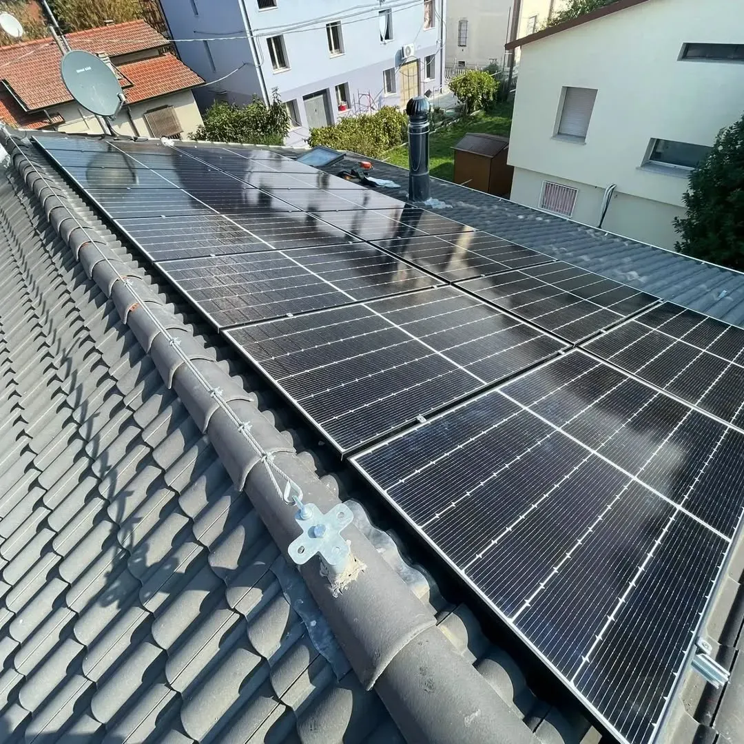 Pannelli solari installati su un tetto tegolato con parabola satellitare e camino.