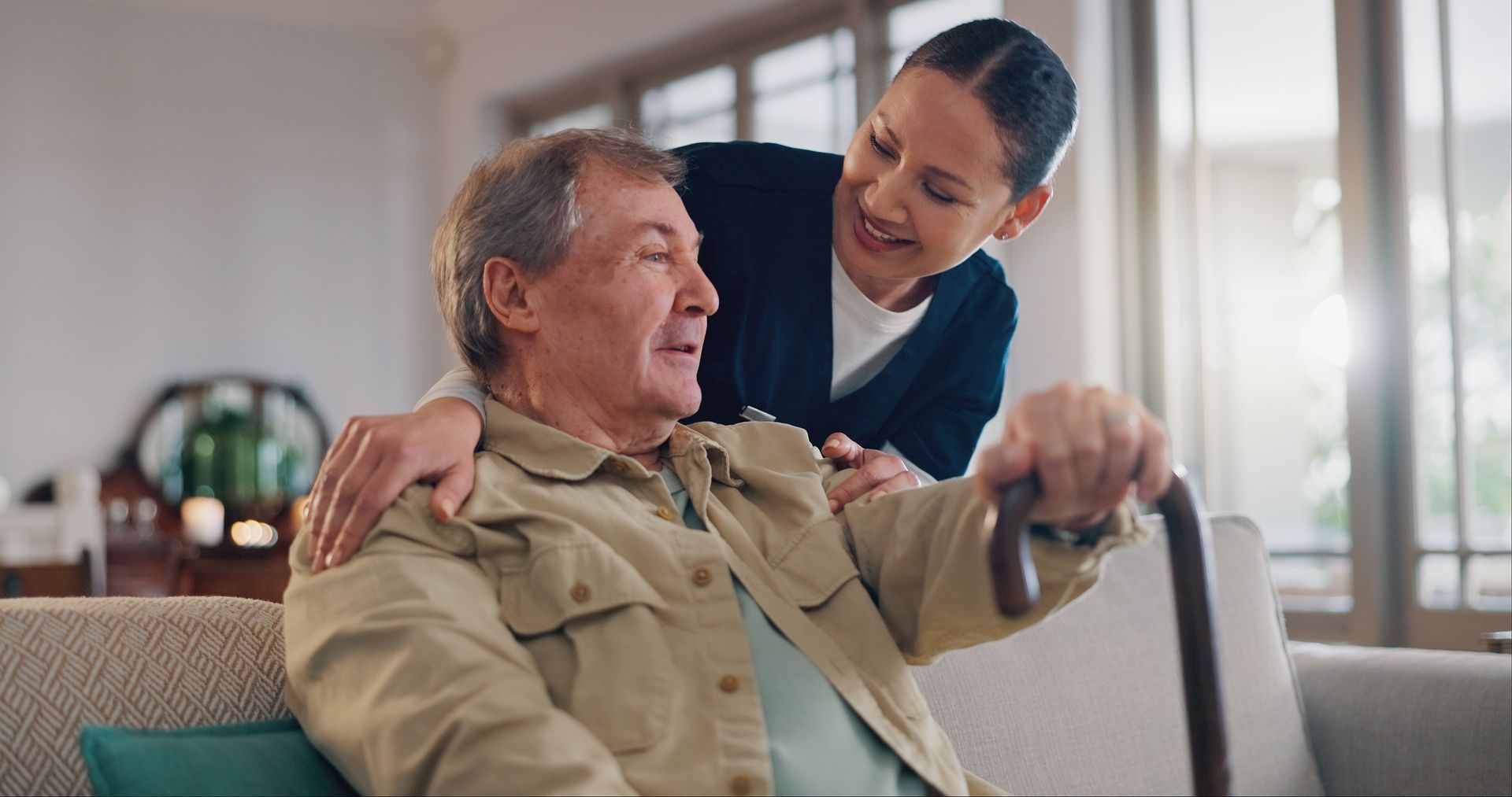 Nurse smiling and talking with a seated patient in a bright living room