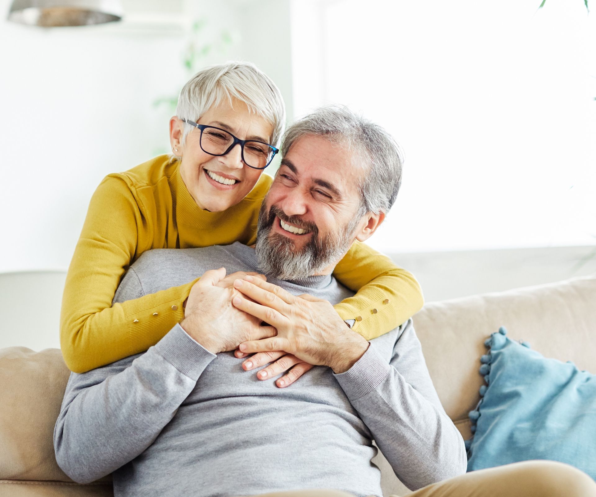 Smiling couple hugging on a couch in a bright living room