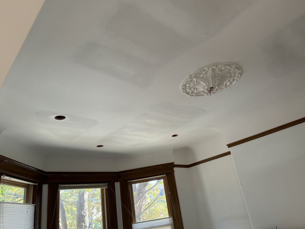 A man is working on a ceiling in a living room.