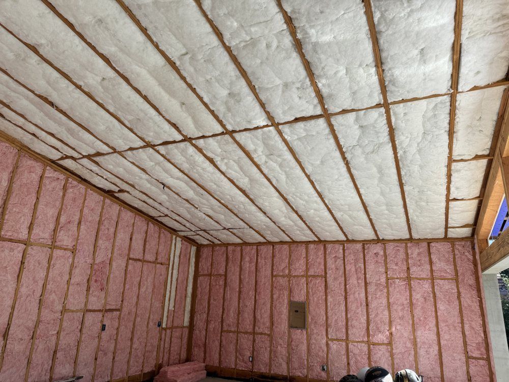 A man wearing a mask is insulating the ceiling of a house.