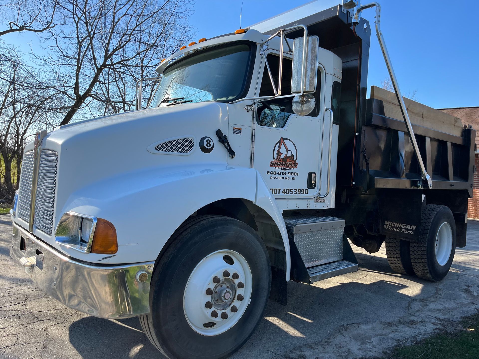 White dump truck parked outdoors on a sunny day, front-left view with a black cargo bed