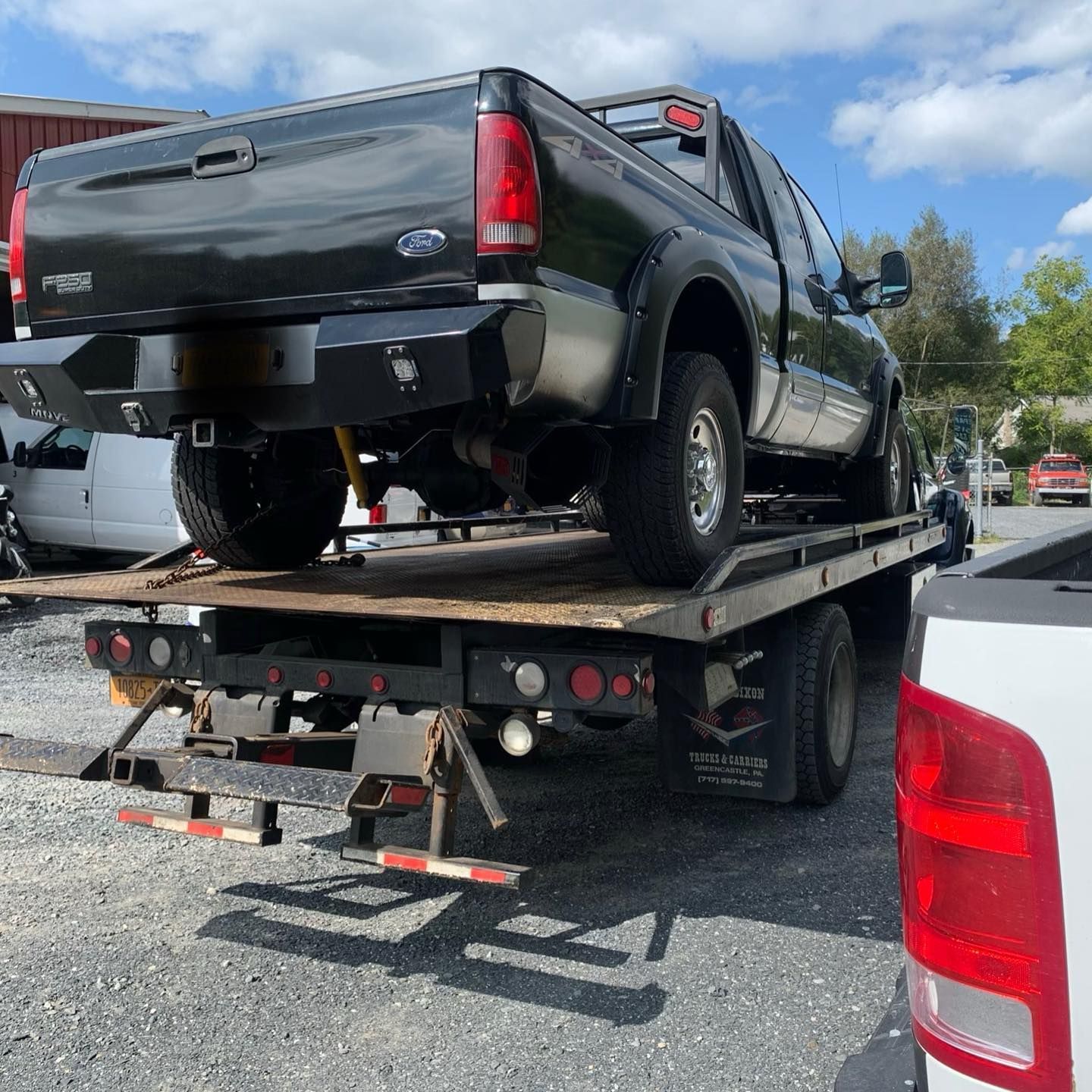 Black Ford truck on a flatbed tow truck outdoors on a sunny day. Black Ford truck on a flatbed tow truck outdoors on a sunny day.