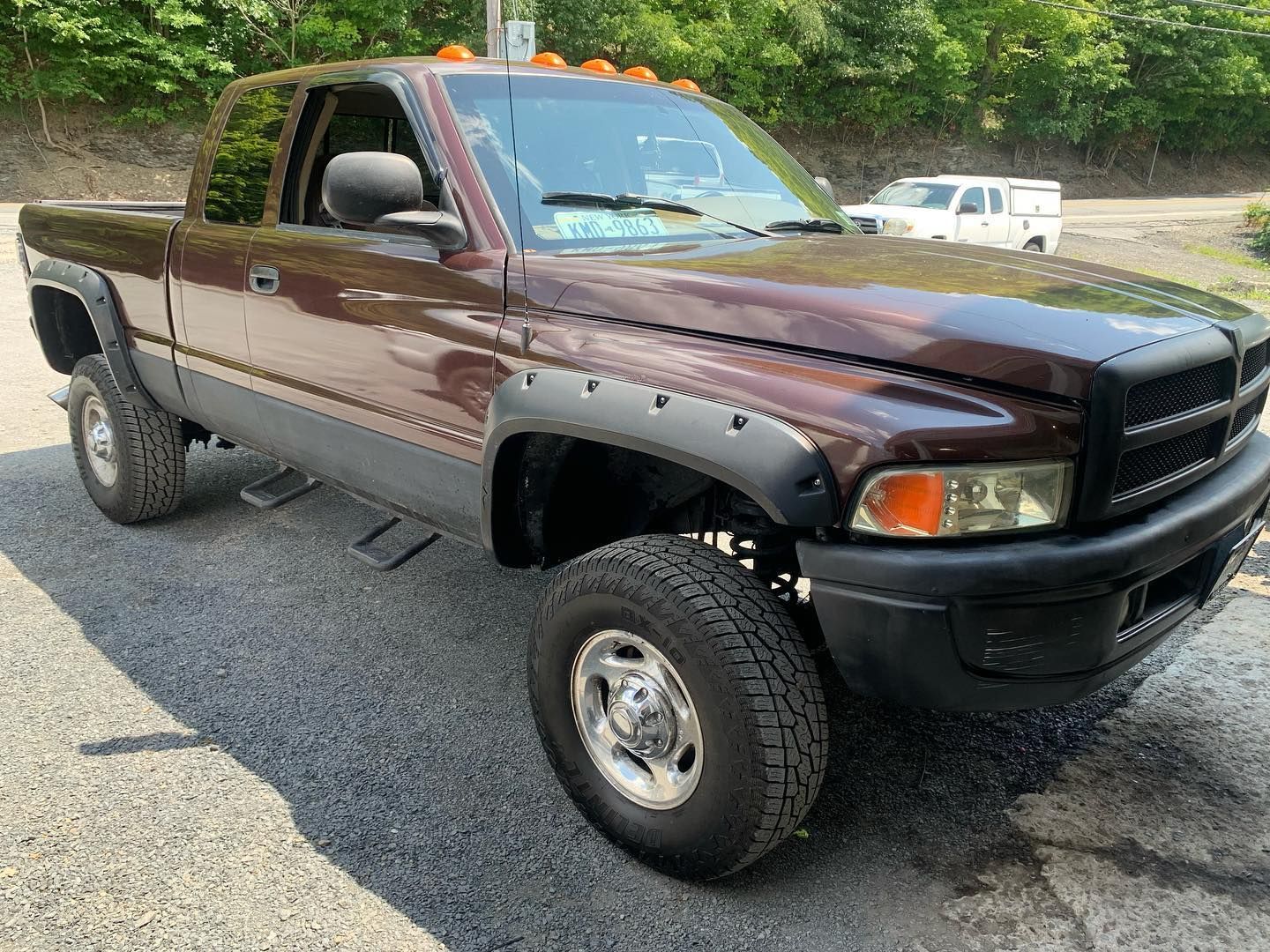 Brown Dodge Ram truck parked on asphalt, black fender flares, side steps, and small cab lights. Brown Dodge Ram truck parked on asphalt, black fender flares, side steps, and small cab lights.