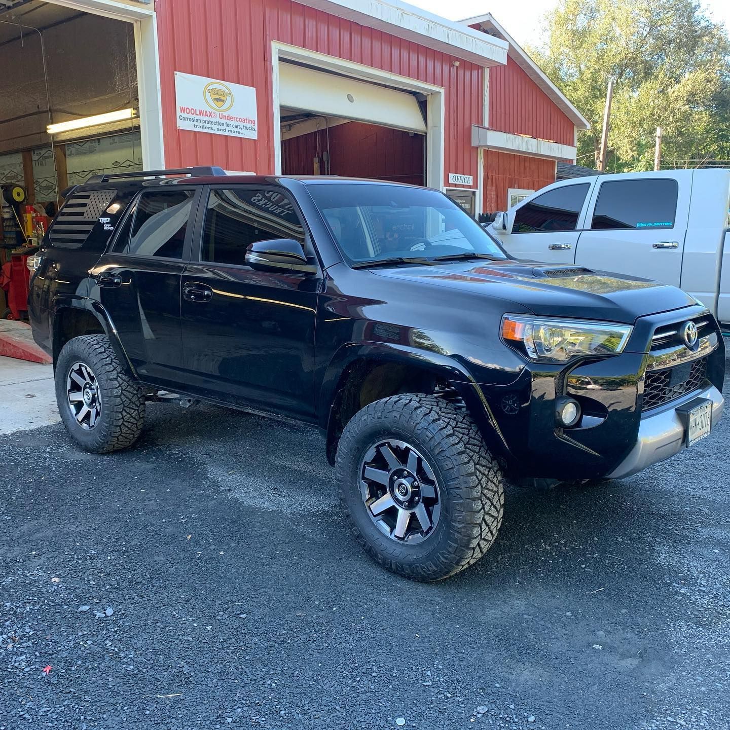 Black Toyota 4Runner SUV parked on gravel in front of a red building with a garage door. Black Toyota 4Runner SUV parked on gravel in front of a red building with a garage door.