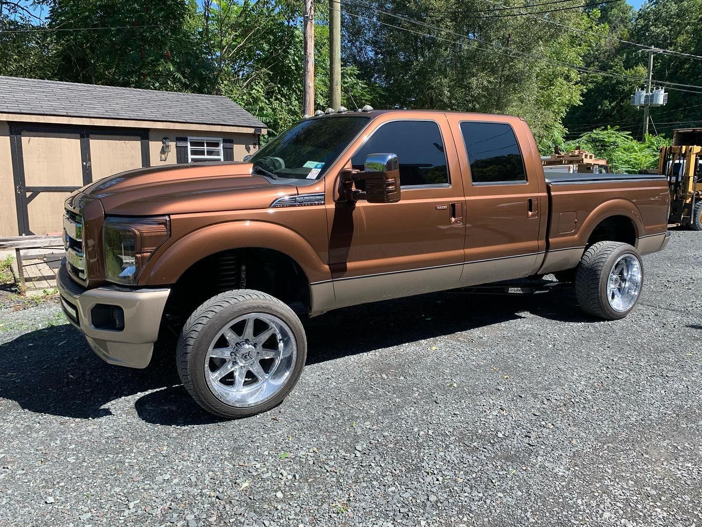 Brown and tan Ford truck with chrome wheels parked on gravel. Brown and tan Ford truck with chrome wheels parked on gravel.